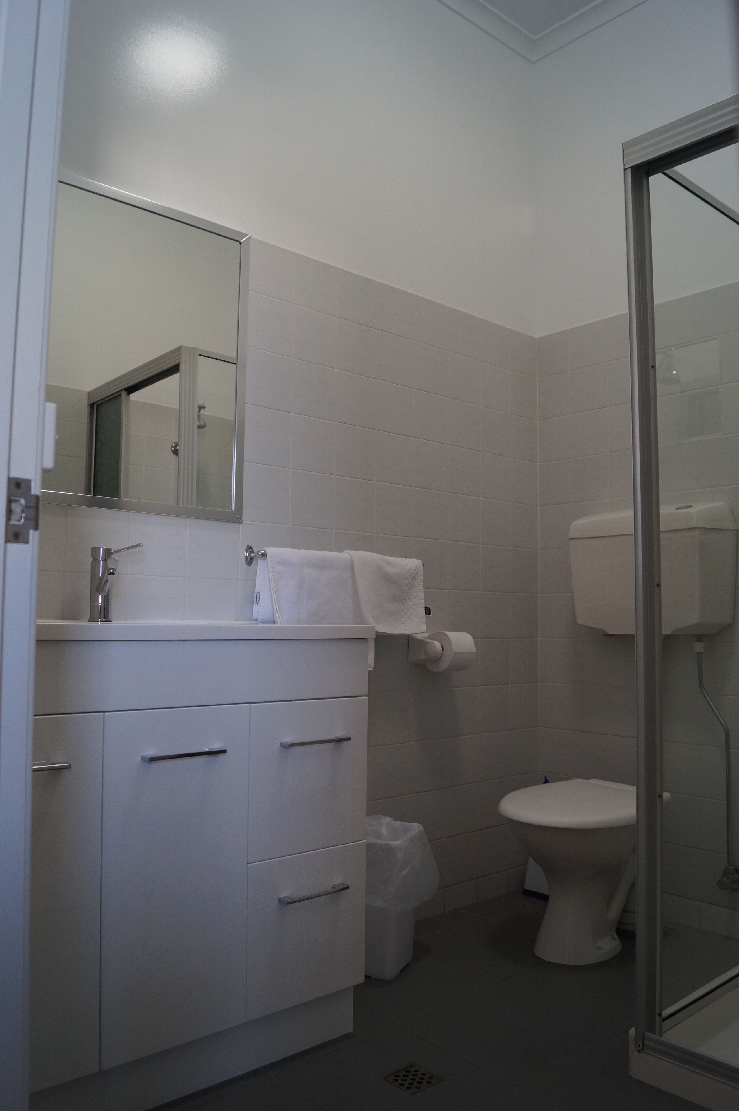 Un baño con lavamanos, espejo y retrete blancos.
