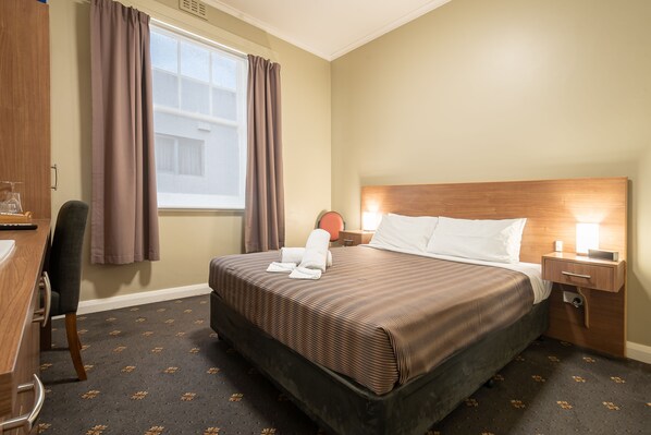 A hotel room with a large bed, a desk, and a chair.
