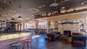 A spacious bar area with a stone fireplace, leather seating, and a bar counter with stools. - Formby Hotel (Devonport)