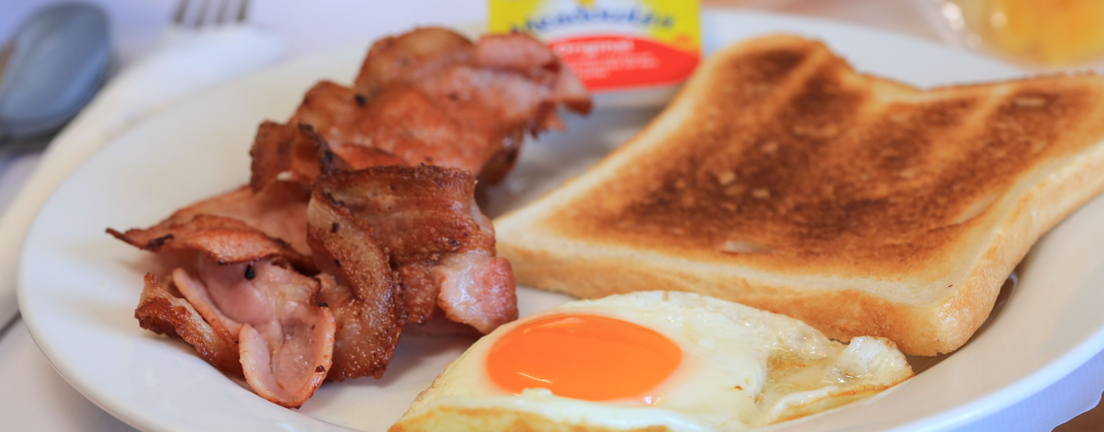 A plate with bacon, toast, and a fried egg.