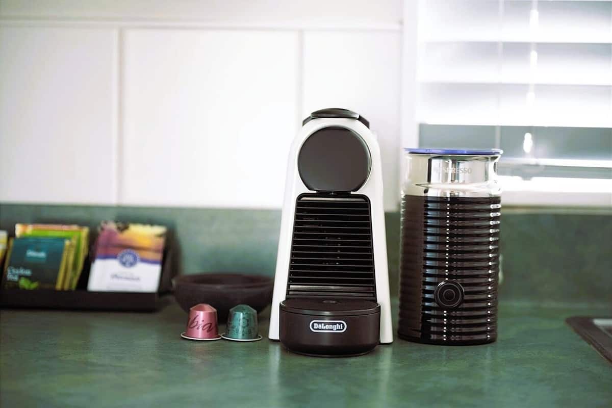 A kitchen counter with a coffee maker, a kettle, and a set of tea cups.