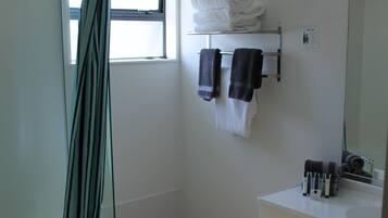 Une salle de bain avec une douche, un lavabo et un porte-serviettes.