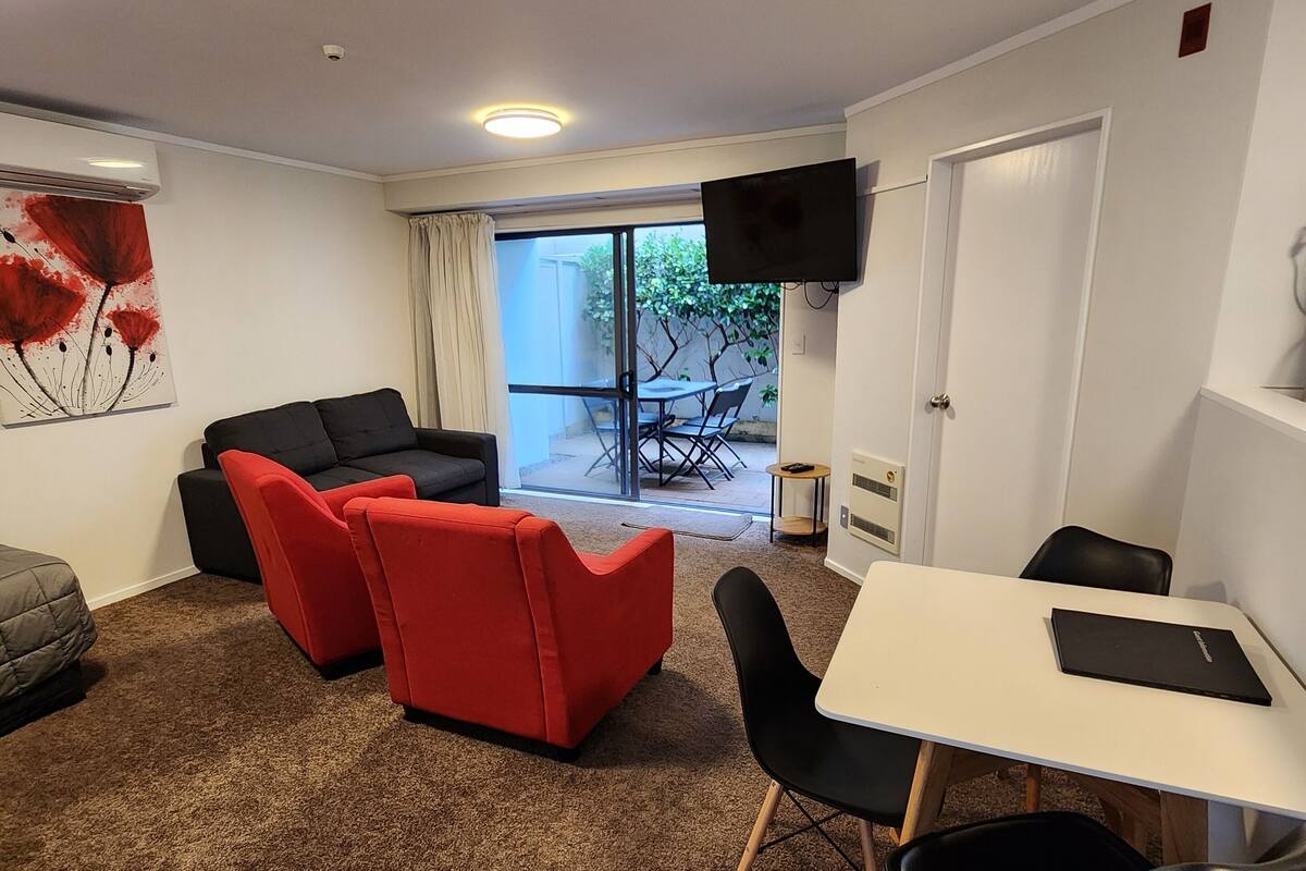 A modern living room with a sofa, chairs, a table, and a TV.