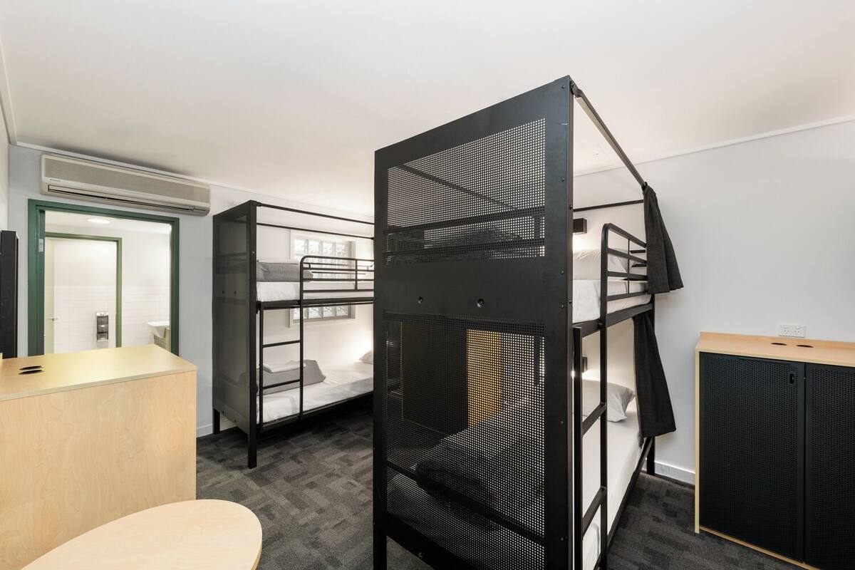 Une chambre de dortoir équipée de lits superposés, d’un bureau, d’une chaise et d’une armoire.
