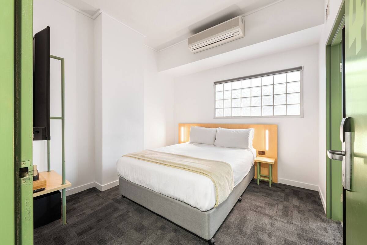 Une chambre d’hôtel avec un lit, une table de chevet, une télévision et une fenêtre.