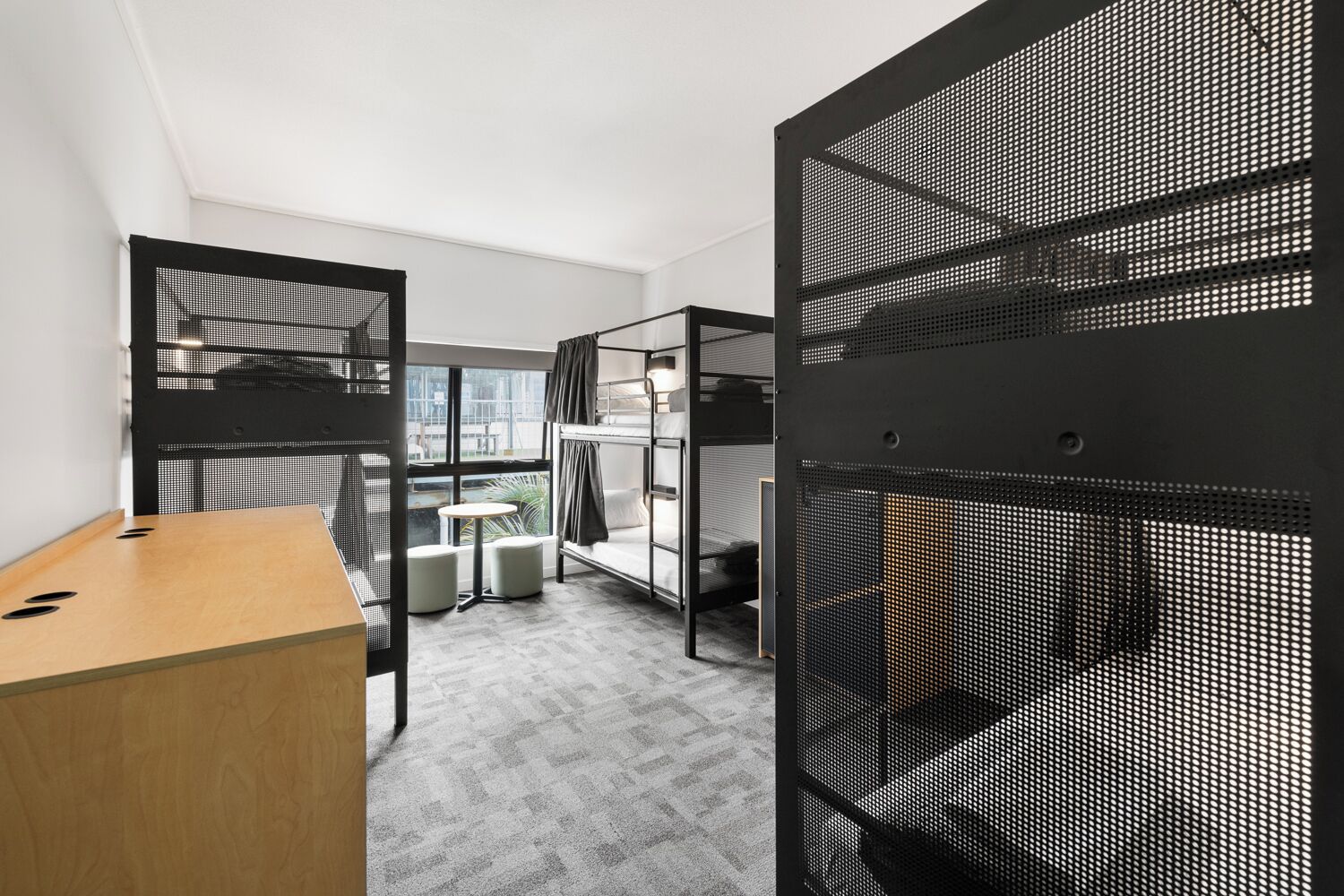 Una habitación de hotel moderna con literas, un escritorio y una pequeña mesa.