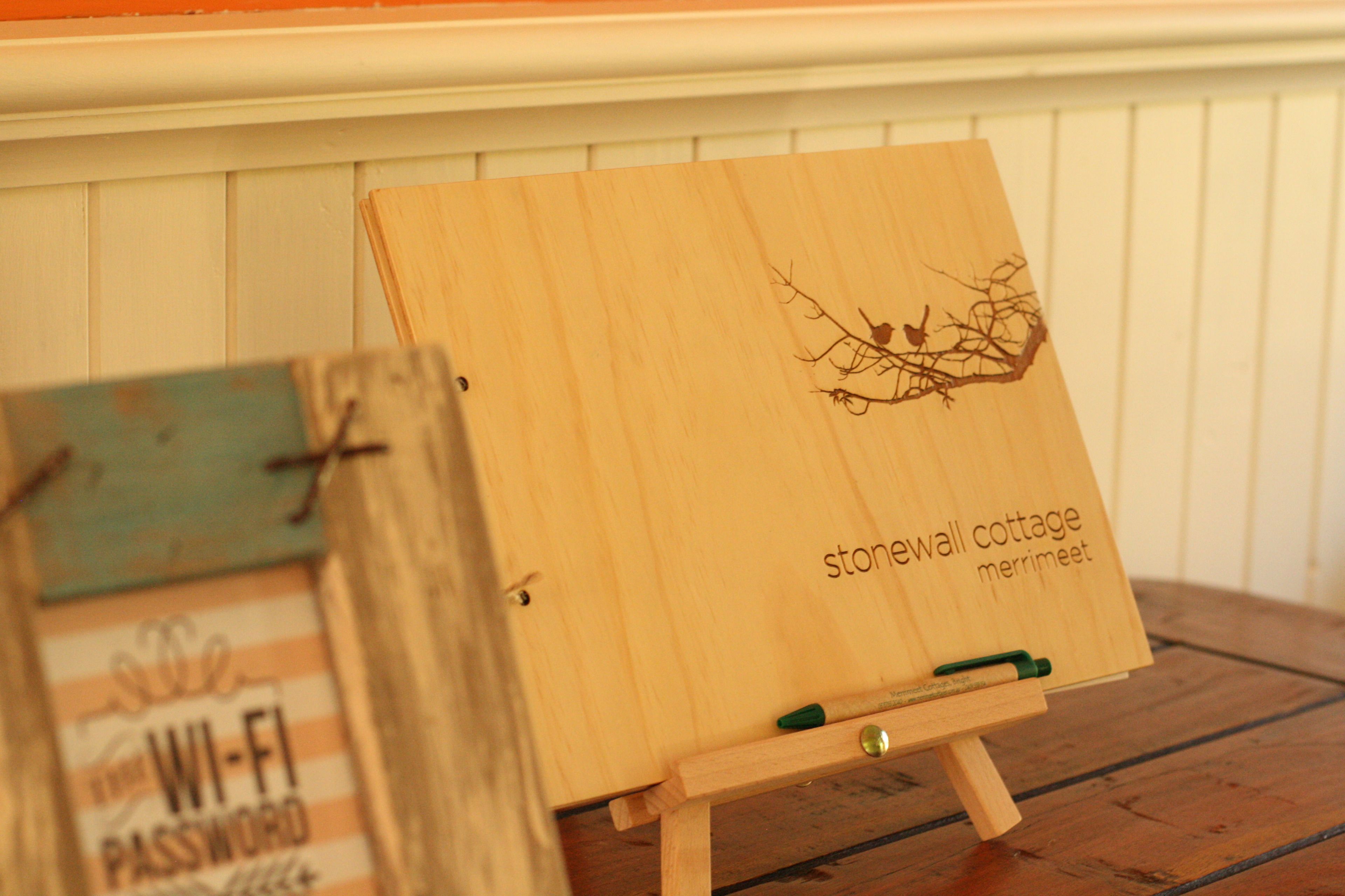 A wooden easel with a branch design and text reading "stonewall cottage merrimee".