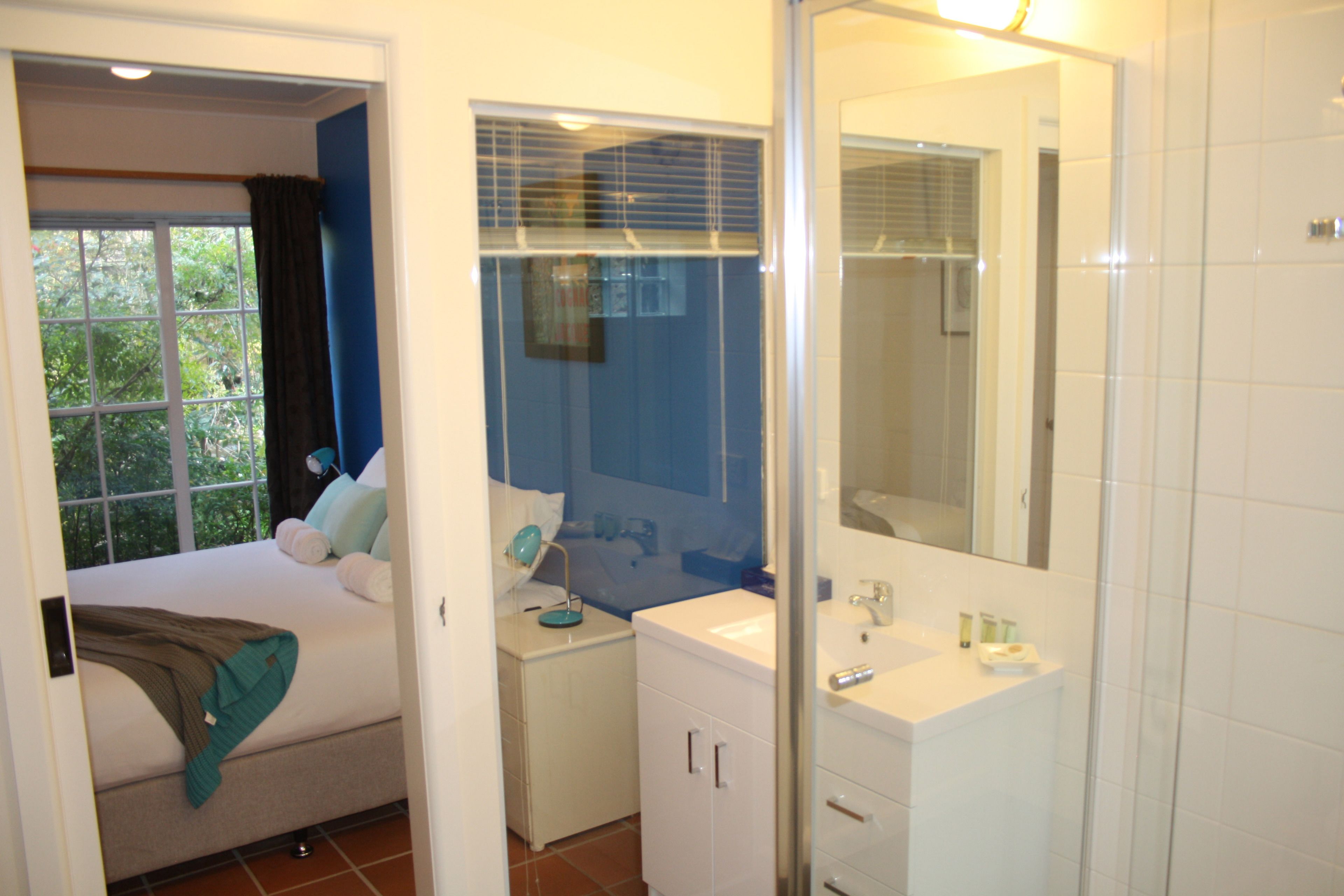 Une chambre à coucher avec un lit, une table de chevet, une commode et une fenêtre avec des rideaux.
