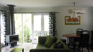 A living room with a sofa, a table, and a fireplace. - Merrimeet Cottages (Bright)