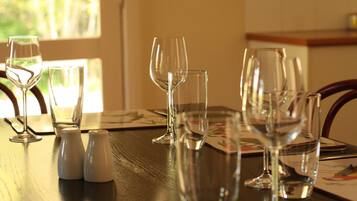A dining table with several empty wine glasses and salt shakers.