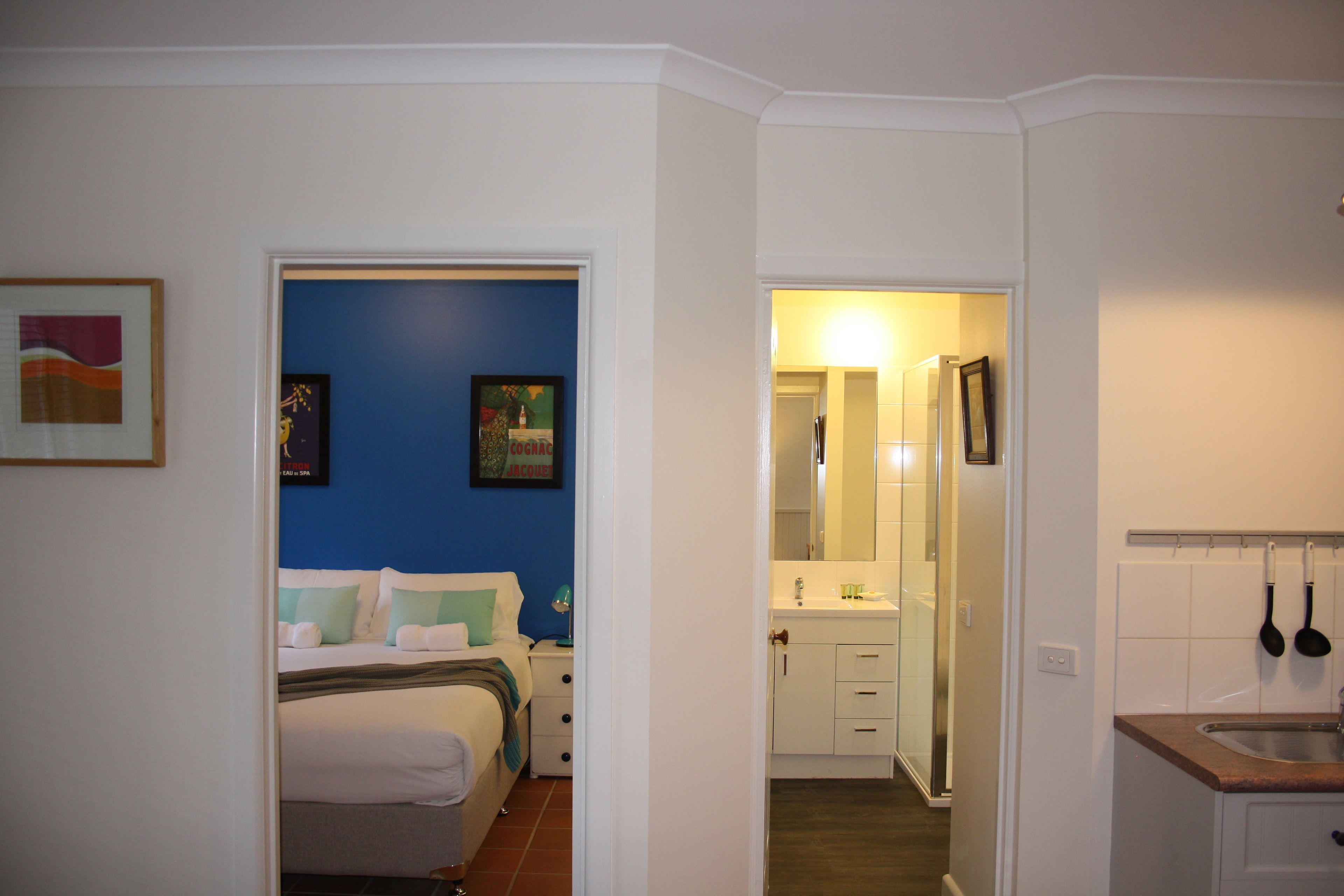 Habitación de hotel con cama, mesita de noche y baño visible a través de una puerta abierta.
