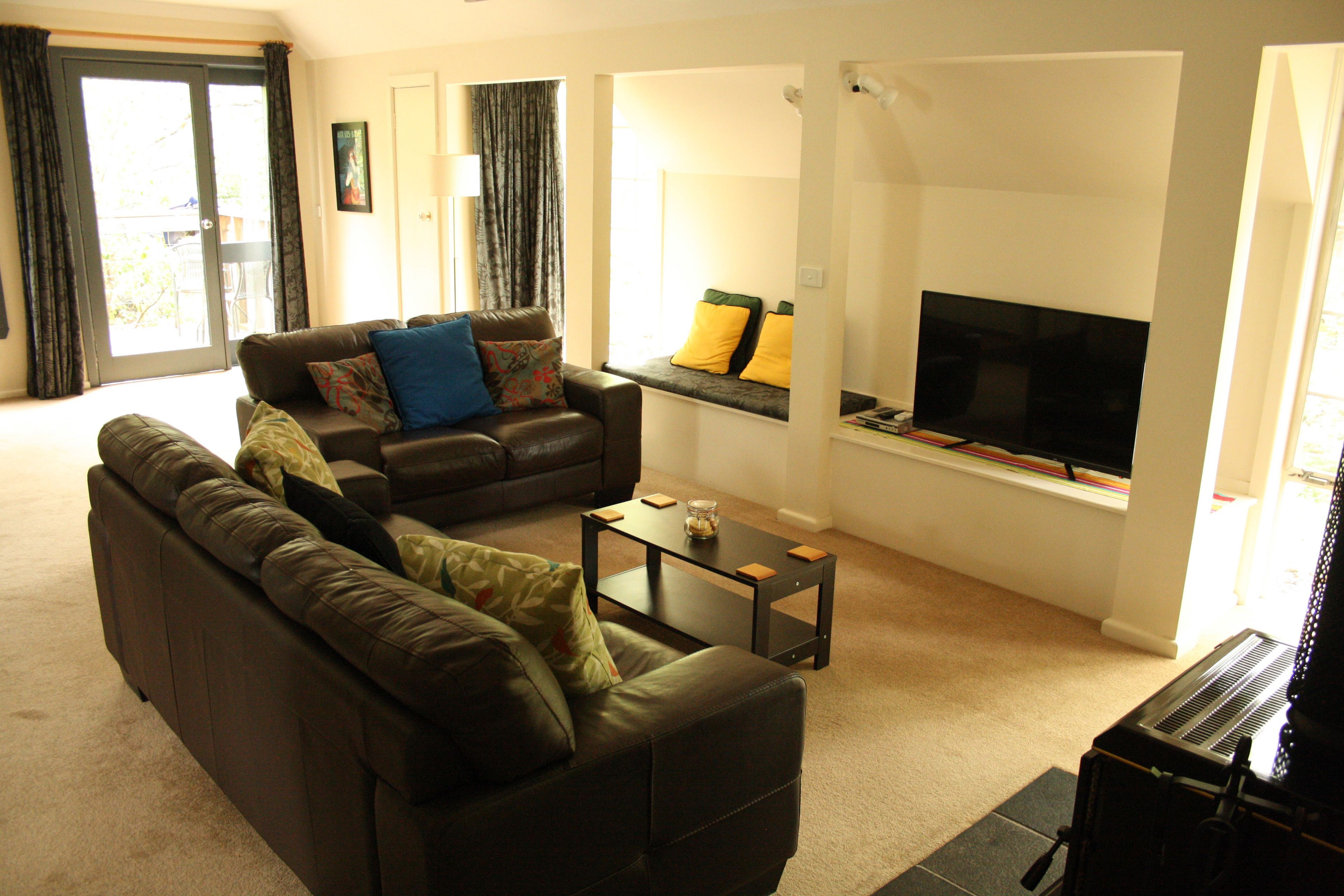 A living room with a sofa, a coffee table, and a flat-screen TV.