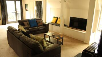 A living room with a sofa, a coffee table, and a flat-screen TV.