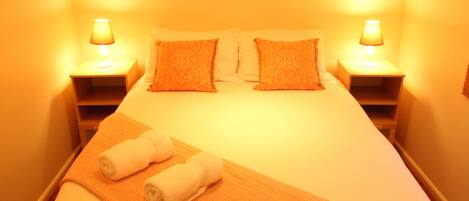 A hotel room with a bed, two bedside lamps, and a blanket.