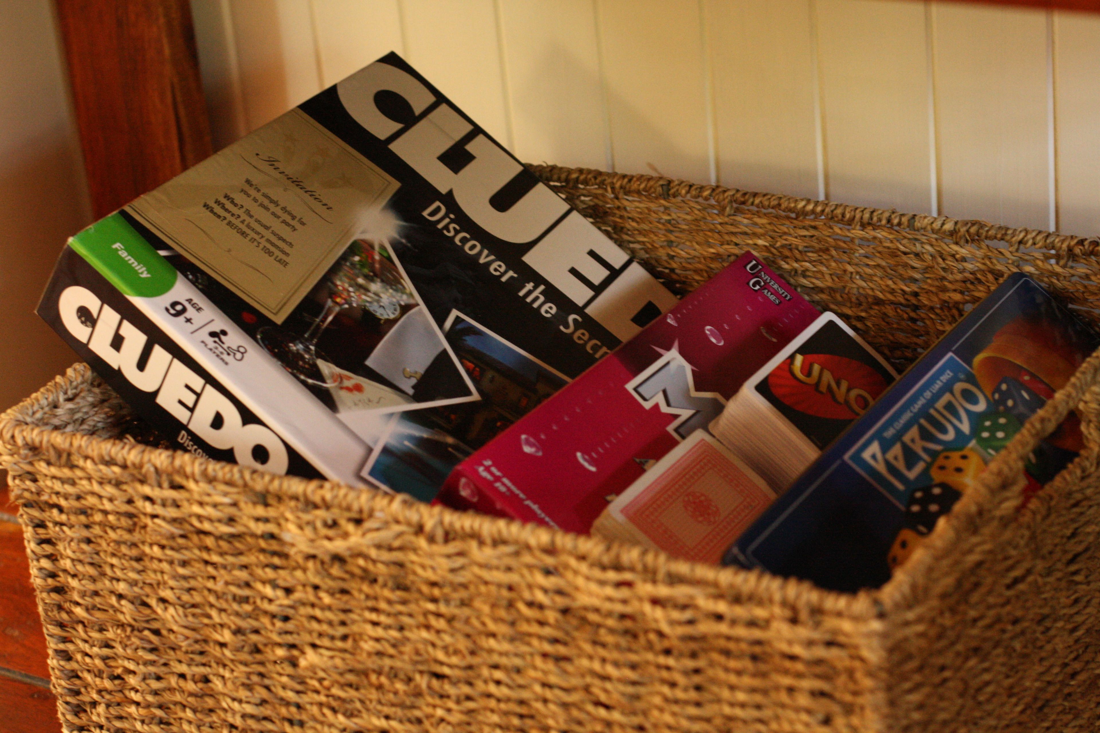 A woven basket containing various board games, including Clue and Uno.