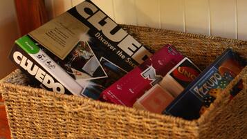 A woven basket containing various board games, including Clue and Uno.