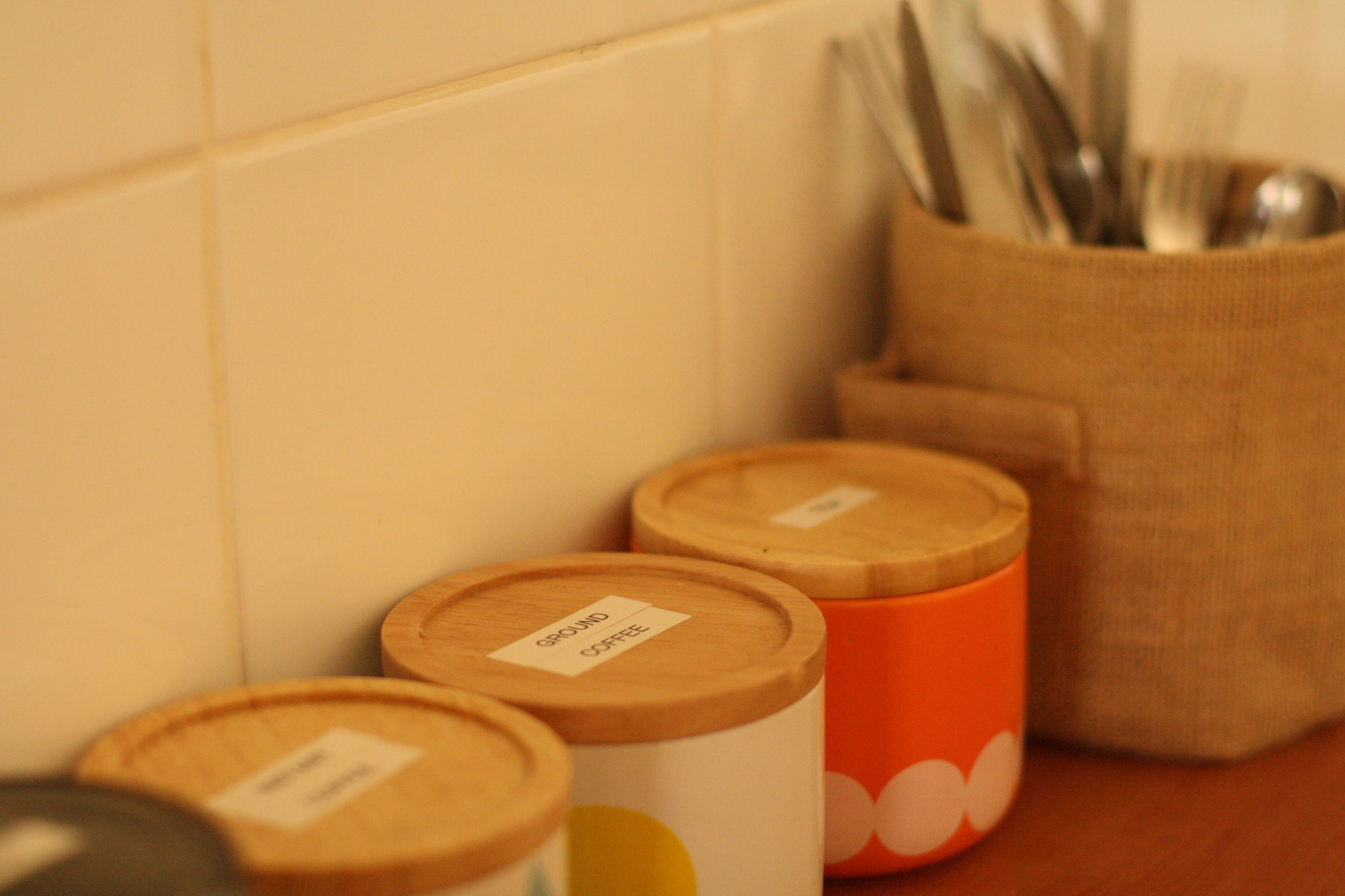 Tres recipientes, uno naranja y dos de madera, sobre una encimera de cocina.