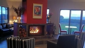 Amplia sala de estar con chimenea, un sofá y vistas al exterior.
