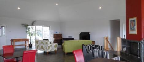 A spacious indoor area with a dining area, seating, and a fireplace.
