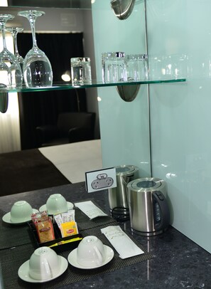 Un espace d’accueil d’hôtel avec une vitrine exposant des verres à vin, une machine à café et un menu.