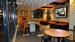 Un área lounge moderna con chimenea, asientos y un televisor montado en la pared.