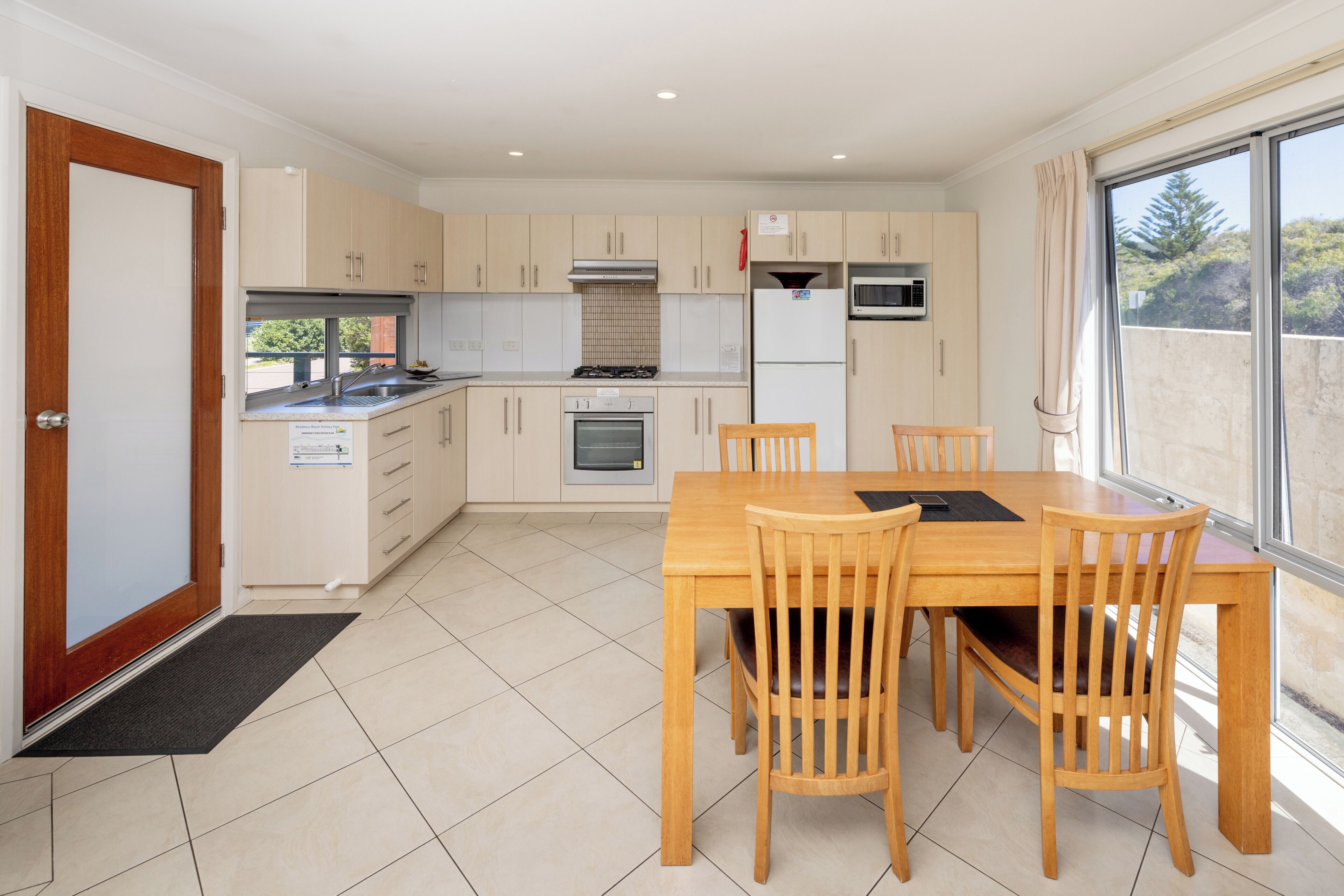 A modern kitchen with a dining area, including cabinets, a stove, oven, microwave, and a large window.