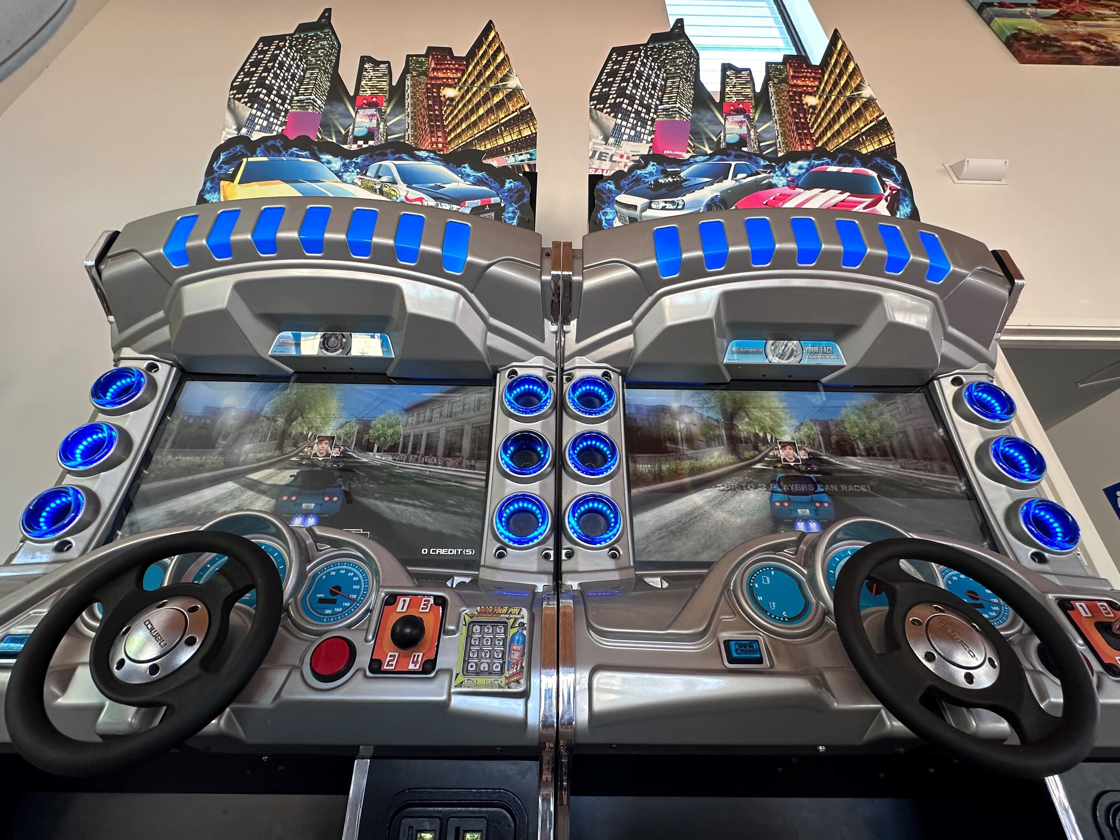 Simulador de carreras con volante, varios botones de control y pantalla mostrando un juego de carreras.