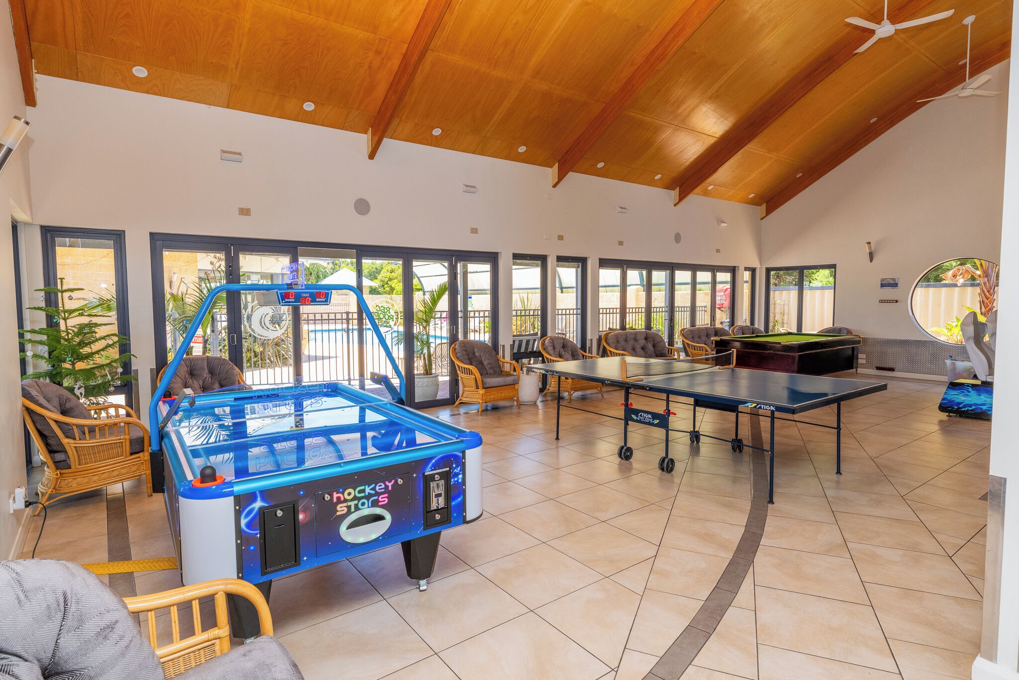 A spacious indoor area with a foosball table, a ping pong table, and wicker furniture.