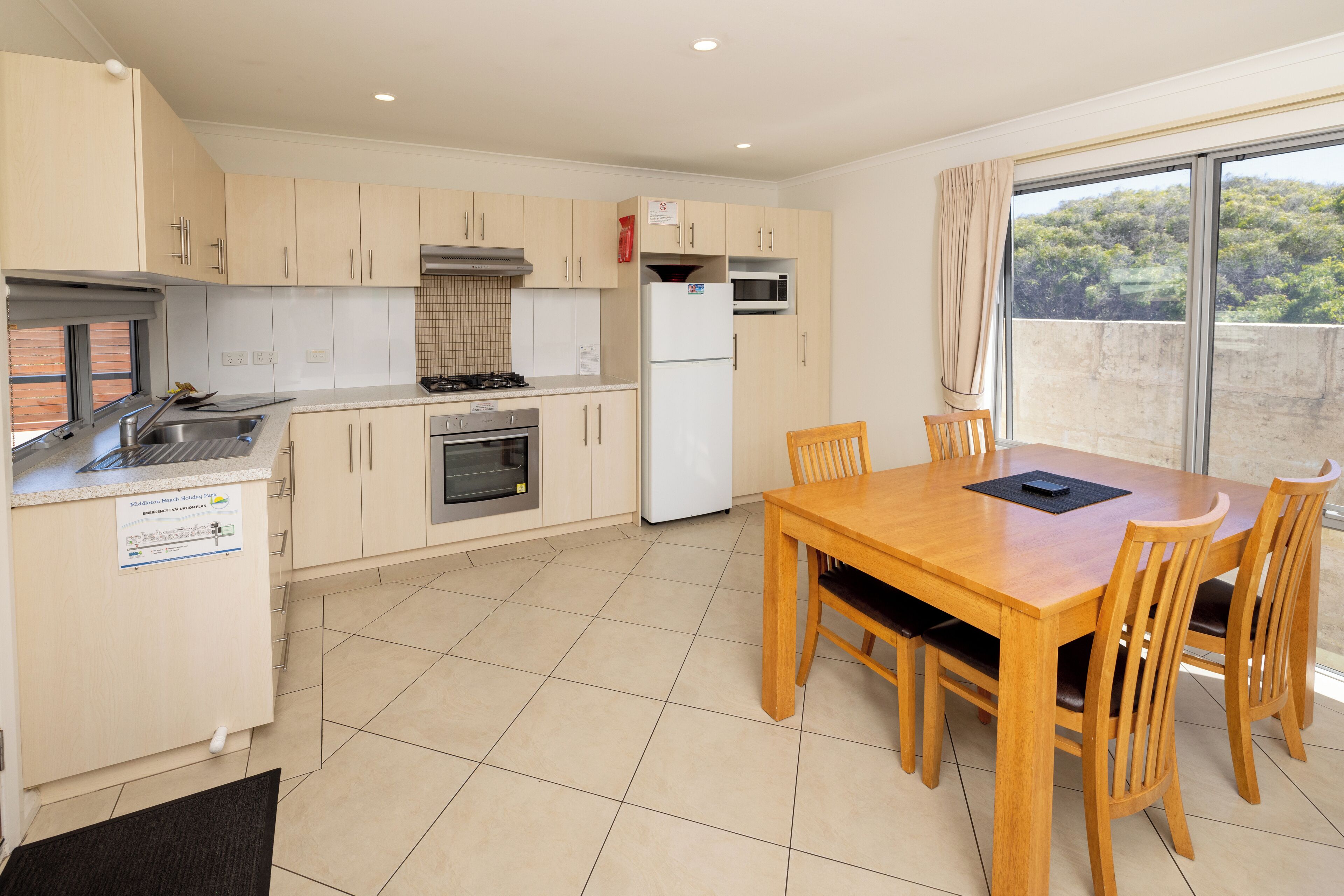 A modern kitchen with a dining area, featuring a large window with a view of the outdoors.