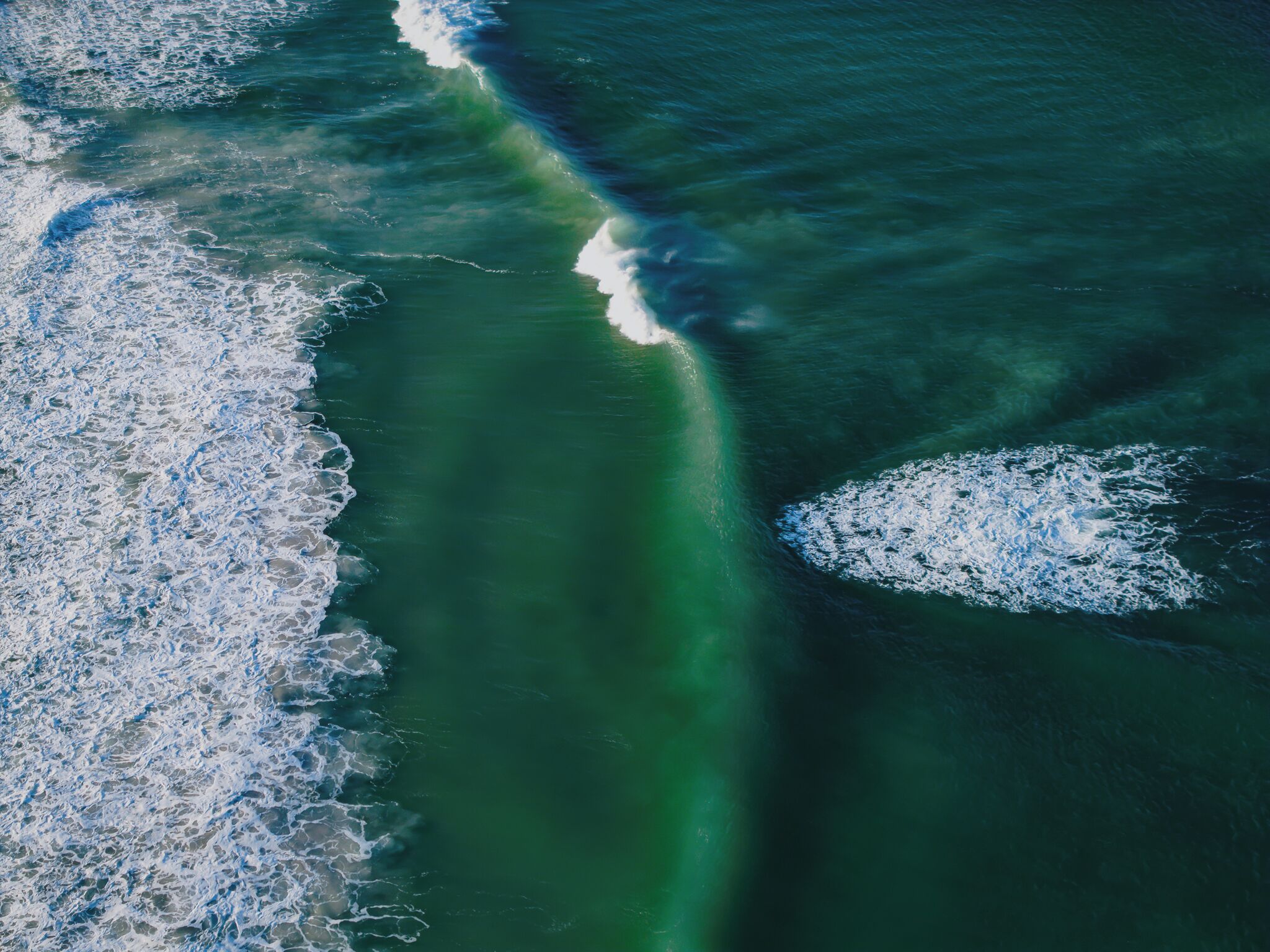 Vista aérea de una zona costera con olas y una clara separación entre la tierra y el mar.