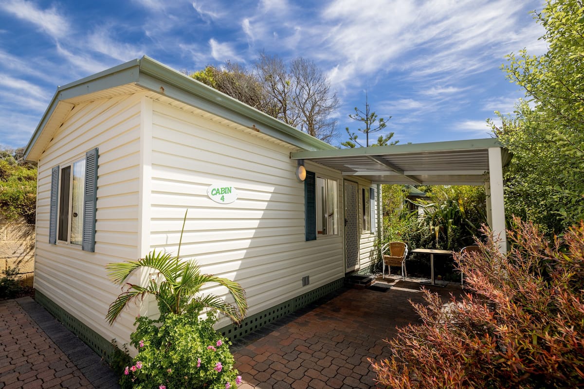 A mobile home with a covered patio area, a small table, and a chair.