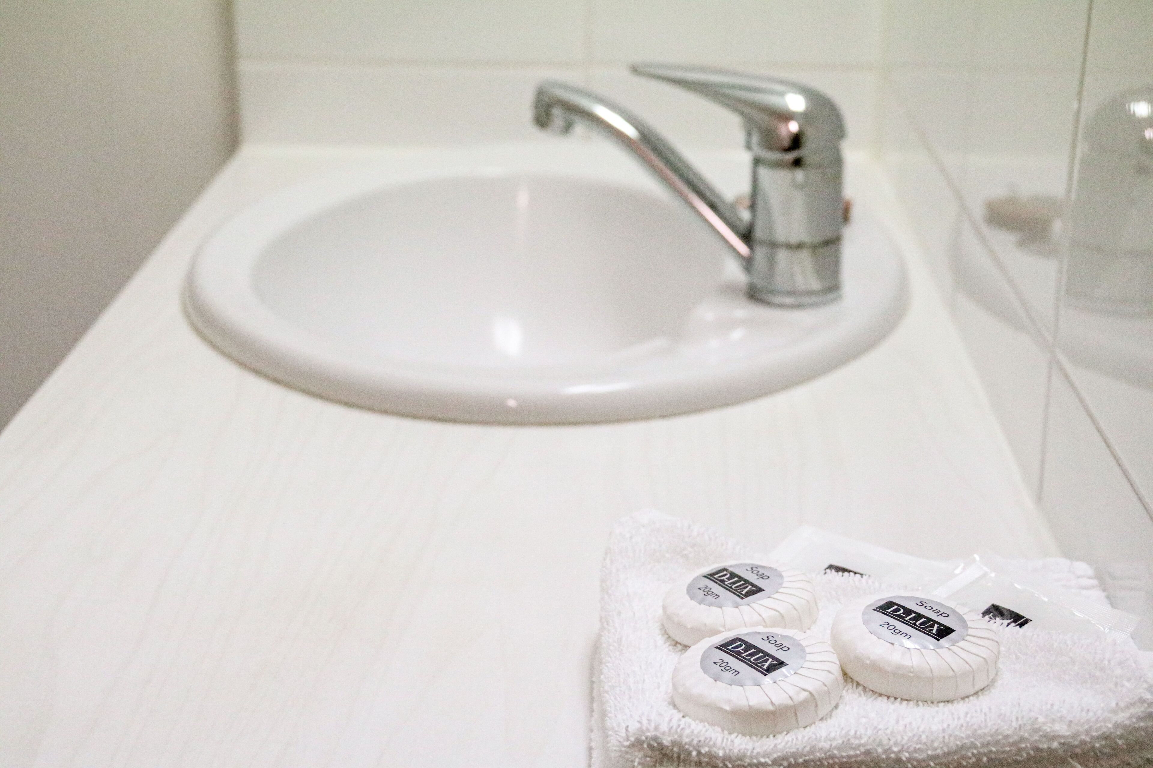 Un lavandino da bagno con un rubinetto e un asciugamano con saponette sopra.