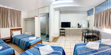 Habitación de hotel con dos camas, un escritorio con computadora, una silla y televisión.