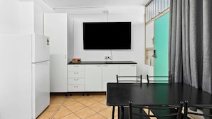 Een kleine keuken met witte kasten, een zwart aanrecht en een zwarte eettafel met stoelen.