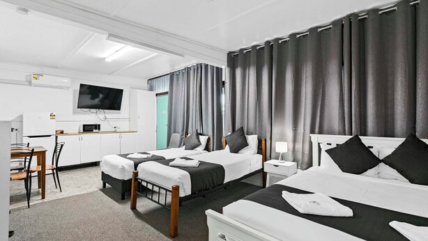 Een hotelkamer met twee bedden, een televisie, een bureau en een stoel.