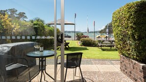 Un patio al aire libre con una parrilla, asientos y vista al mar.