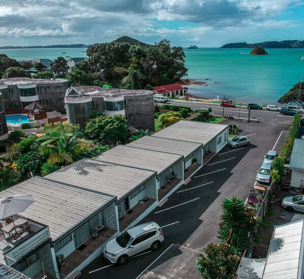 A hotel with a pool, a parking lot, and a view of the sea. - Ala Moana Motel (Paihia)