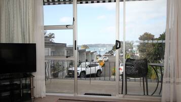 A room with a sliding glass door leading to a balcony with a view of parked cars and boats.
