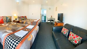 A hotel room with two beds, a sofa, a TV, and a kitchenette. - Kerry's Motel (Rotorua)