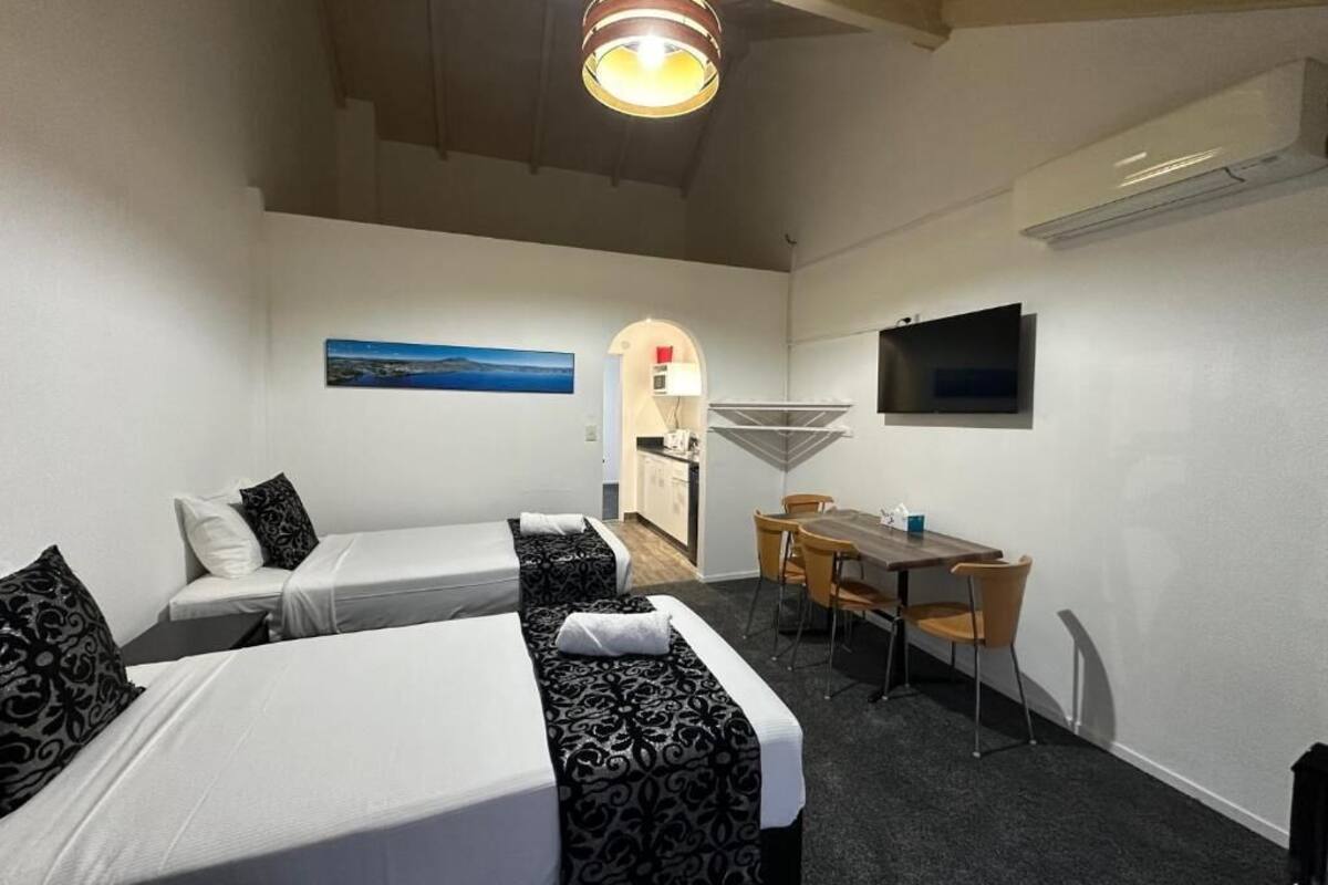 Une chambre d’hôtel avec deux lits, une table à manger, un téléviseur et une vue sur la mer.