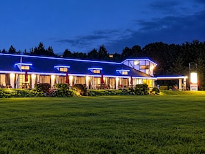 A hotel with a well-lit facade, multiple windows, and a covered outdoor seating area.