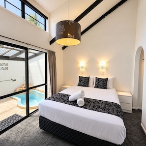 Une chambre d’hôtel avec un grand lit, deux lampes de chevet, une fenêtre donnant sur une piscine et un luminaire au plafond.