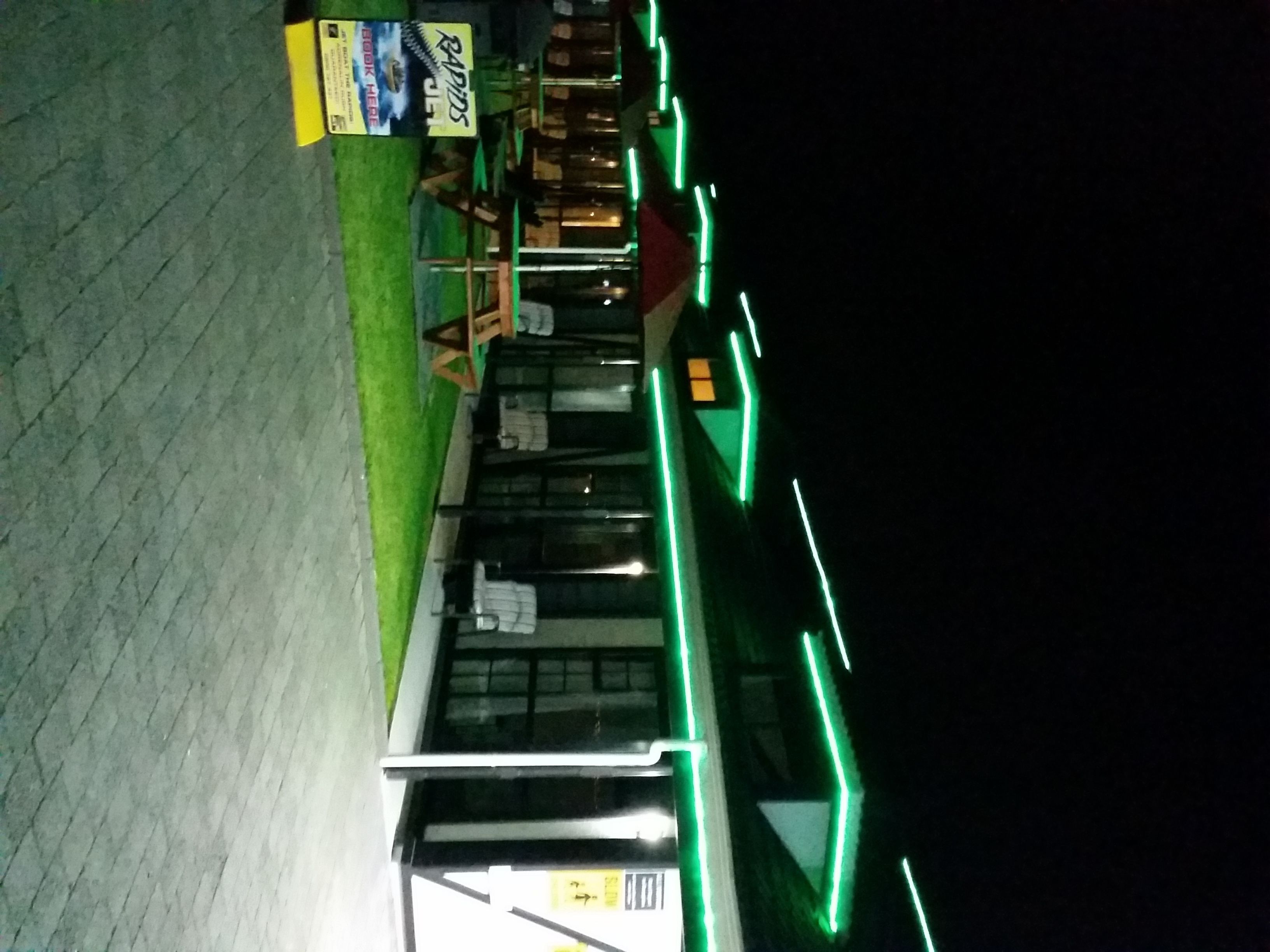 A building with a green-lit exterior, a signboard, and a visible entrance.