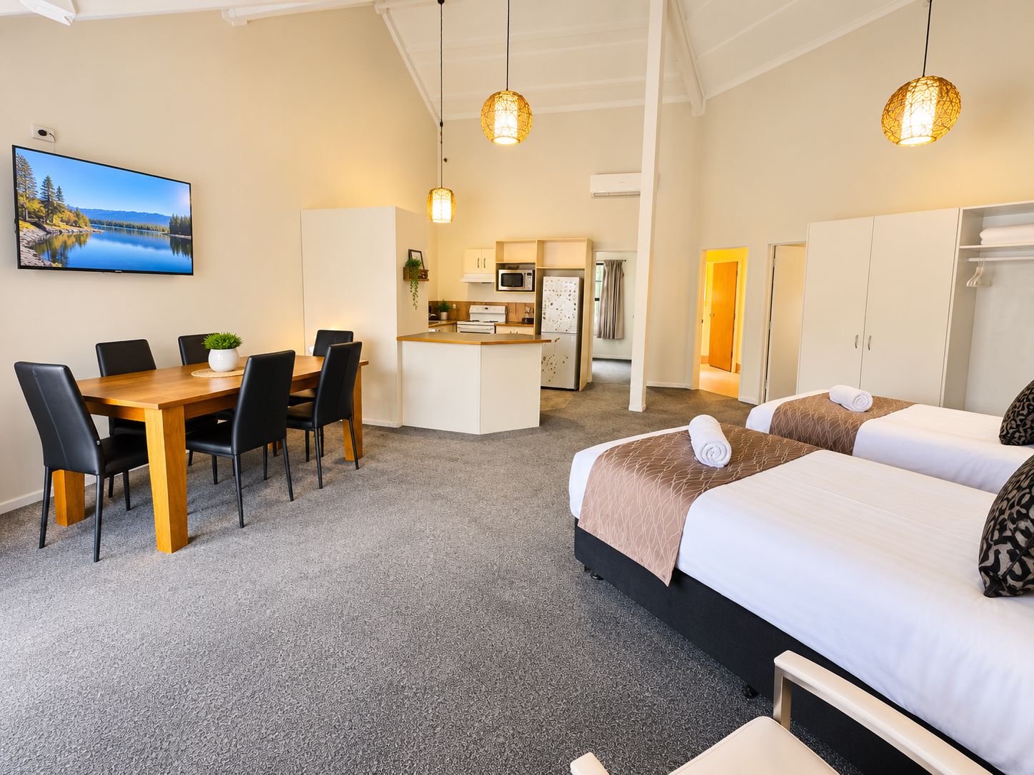 A hotel room with a bed, a desk, and a kitchenette.