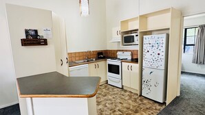 A compact kitchen with a central island, a microwave, a refrigerator, and a hanging light fixture.