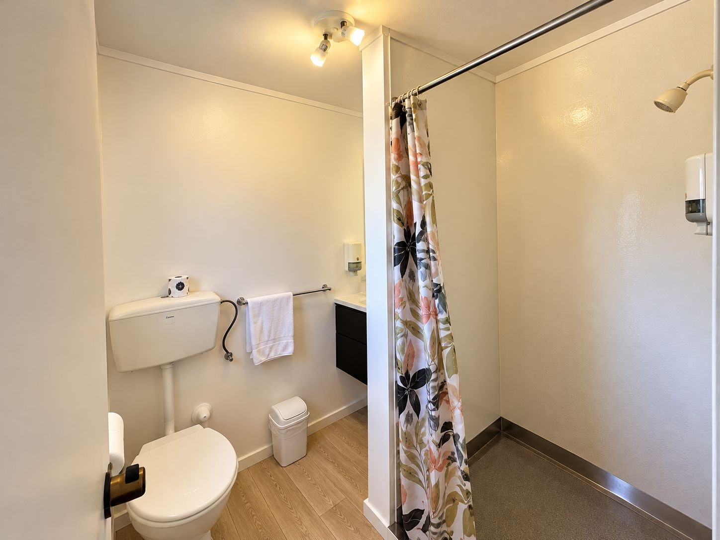 A bathroom with a toilet, a shower curtain, and a towel rack.