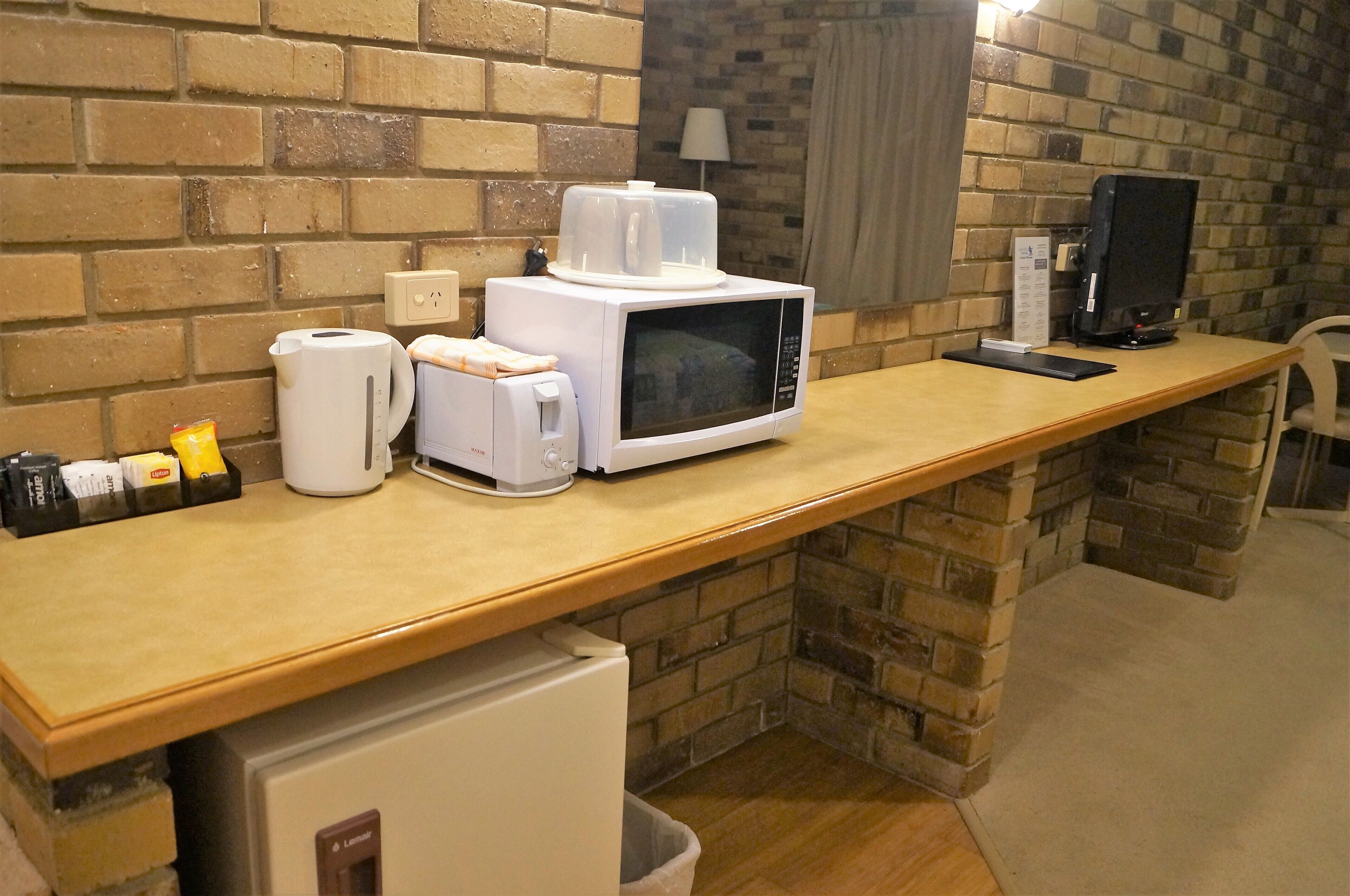 A kitchenette with a microwave, coffee maker, and toaster.