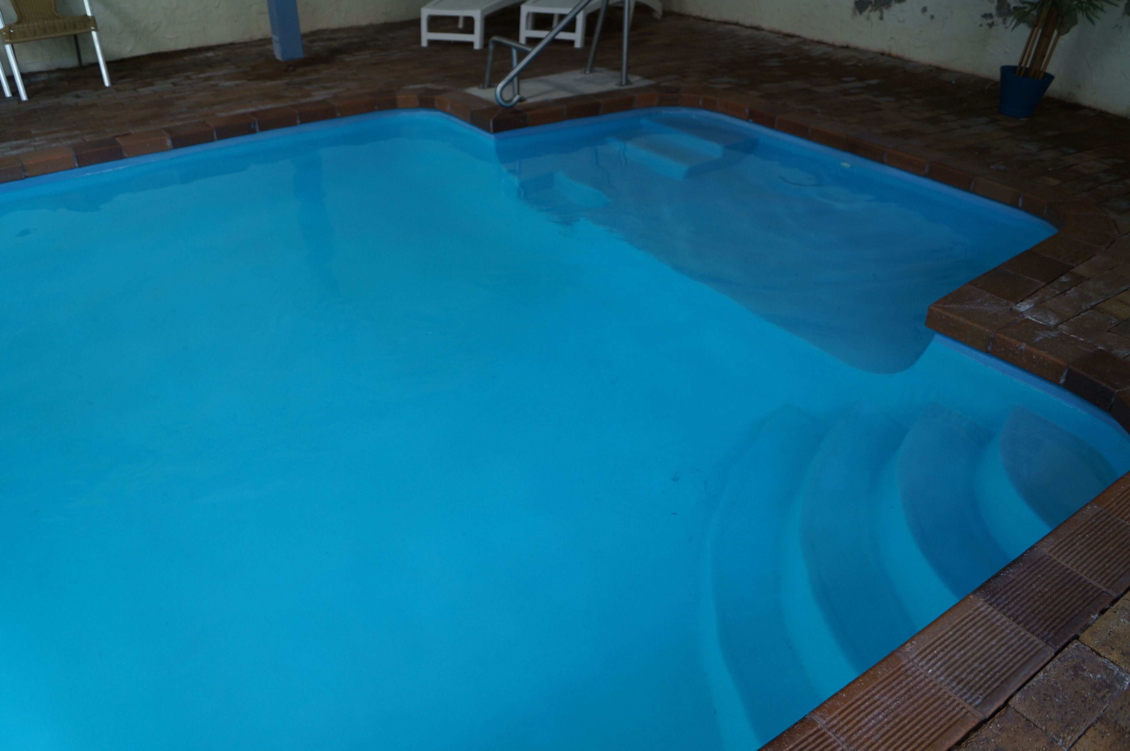 A rectangular swimming pool with a clear blue water surface, surrounded by a brick border.