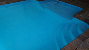 A rectangular swimming pool with a clear blue water surface, surrounded by a brick border.