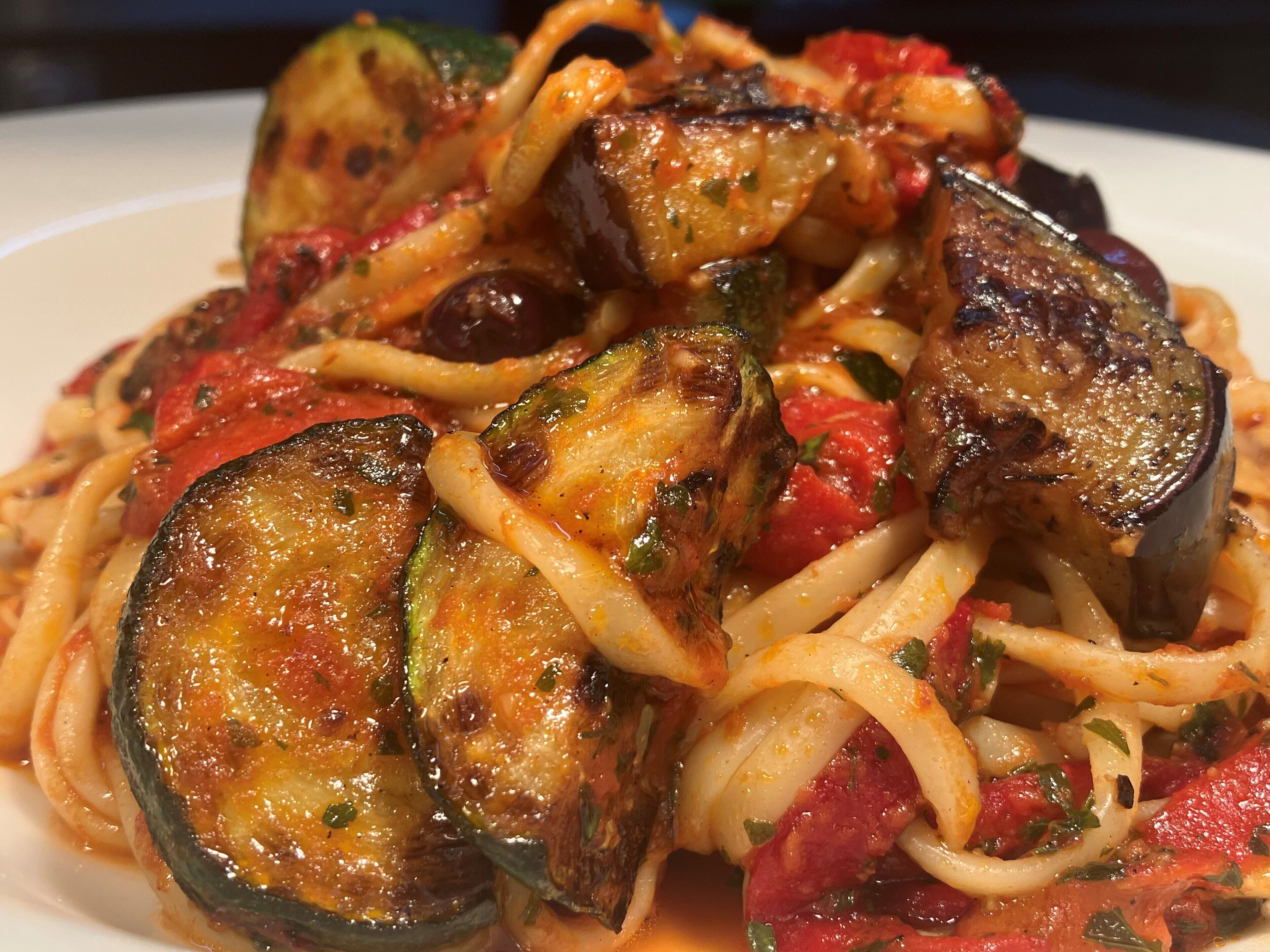 Prato de espaguete com berinjela grelhada e tomates.